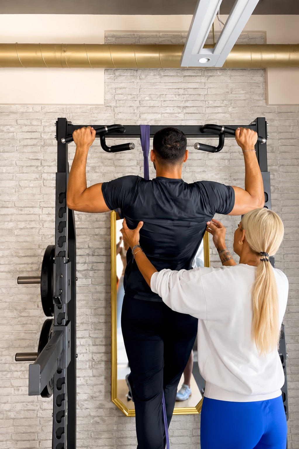 Coach assisting client with pull-up training